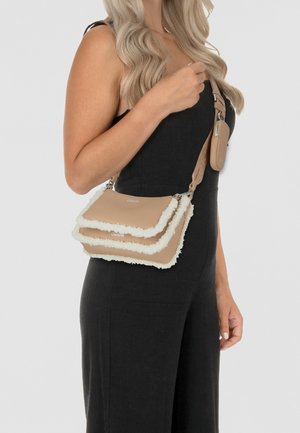 Borsa a tracolla beige con bordi in pelliccia sintetica bianca, caratterizzata da tre strati, tracolla regolabile e tasca con zip attaccata. Texture liscia.