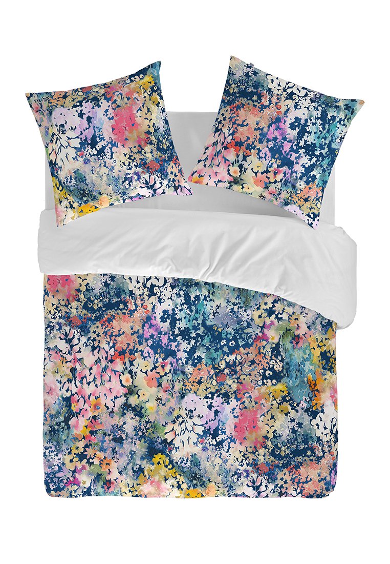 Cubrecamas y fundas de almohada con un diseño vibrante en azules, rosas y amarillos sobre un fondo blanco, con una textura suave.