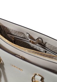 Sac à main gris clair avec texture granuleuse, garnitures dorées, compartiment zippé et doublure intérieure à motif.