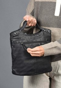 Zwarte leren tote bag met twee handvatten, een voorkant met ritsvak en drukknoopaccenten. Het materiaal is zacht met een gladde textuur.