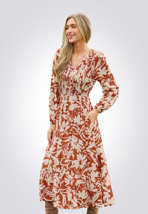 Langes Blumenkleid mit V-Ausschnitt, gerafftem Oberteil und langen Ärmeln. Der Stoff hat eine erdige Rostfarbe mit cremefarbenen Blumenmustern.