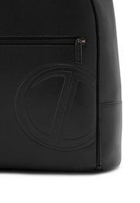 Black leather backpack featuring a front zipper pocket with metal pull tab and embossed circular logo on the lower front panel.