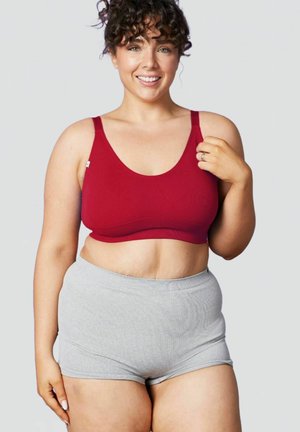 Bra sportivo rosso a coste con spalline larghe e scollatura a barca, abbinato a pantaloni corti in cotone grigio a vita alta. Design semplice e funzionale.