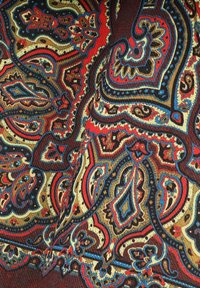 Wzorzysta tkanina z wzorem paisley w kolorze czerwonym, niebieskim, złotym i czarnym na teksturowanym brązowym tle.