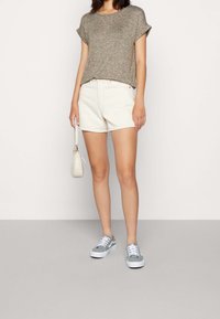 Šedé Texturované tričko, krémové šortky, šedé tenisky s bílou podrážkou, malá světlá taška. Jednoduchý, ležérní outfit v neutrálních barvách.