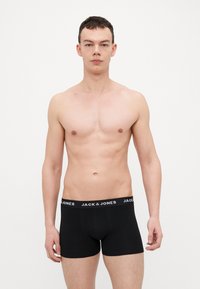 Boxer shorts noirs en coton doux, dotés d'une ceinture élastique de marque blanche avec le texte "JACK & JONES". Texture lisse.