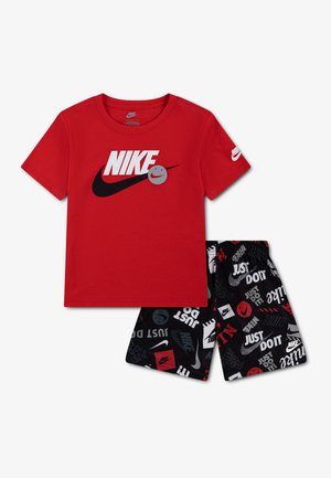 Red short-sleeve Nike t-shirt with black swoosh and smiley face, paired with black shorts featuring white and red Nike logos and "Just Do It" text.