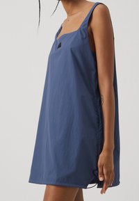 Modrá bezrukávová šaty vyrobené z lehkého materiálu, s čtvercovým výstřihem a bočním stahováním pro úpravu velikosti.