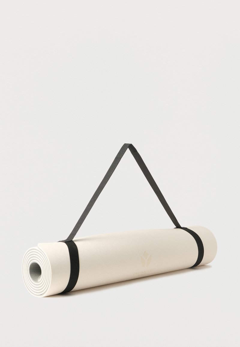 Tapis de yoga beige roulé, fixé avec deux sangles noires et doté d'une poignée de transport, sur un fond clair uni.