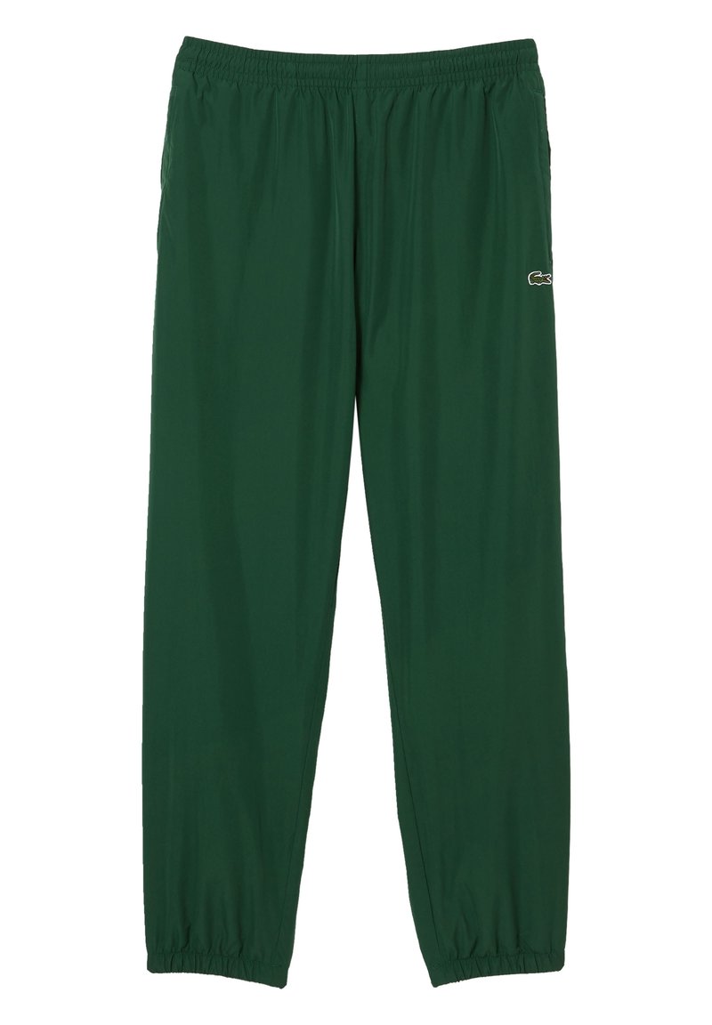 Gröna sportbyxor i lätt tyg, med elastisk midja och muddar. Lacoste-logotyp i vitt på övre benet.