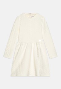 Kremowa sukienka z długim rękawem, z teksturowanym wzorem warkocza, rozkloszowaną spódnicą i małym serduszkiem przy bocznym szwie.