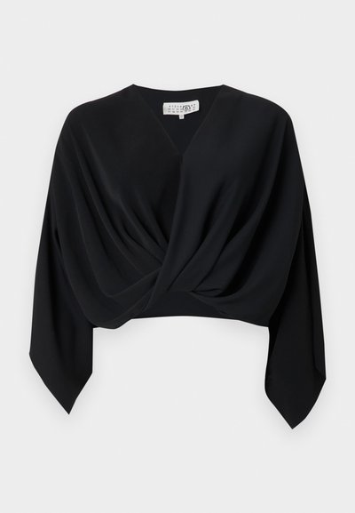 Fekete, rövid felső puha anyagból, mély V-nyakkivágással, redőzött elülső résszel és hosszú, hegyes végű ujjakkal. Nincsenek látható minták vagy fémkellékek.