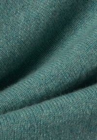 Teal gebreide stof met een zachte textuur, met een subtiel geribbeld patroon en strengen van verschillende tinten, wat diepte en dimensie creëert.