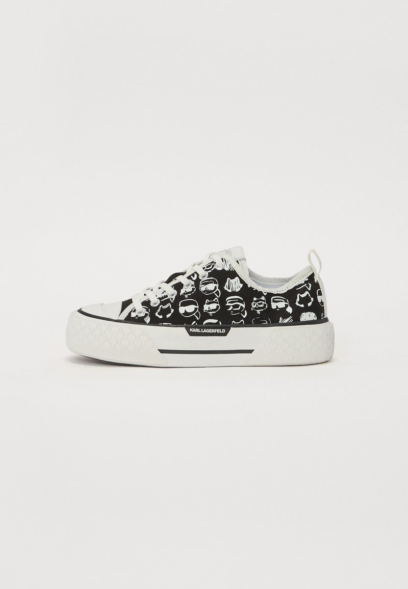 Must musta sneaker mustvalge karikatuuriga trükistega, valge tald ja kontrastsed mustad detailid; sisaldab paelu ja sildit küljes.