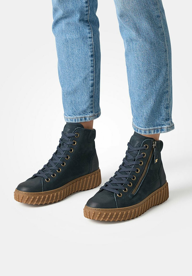 Baskets montantes en cuir bleu foncé avec des accents texturés, lacets à l'avant, fermeture éclair sur le côté, et une semelle en caoutchouc marron épaisse.