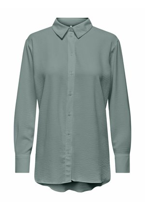 Ilgi piedurkņu pogu krekls bālganā ziloņkaula krāsā ar klasisku apkakli, strukturētu audumu un izliekta apakšmalu.