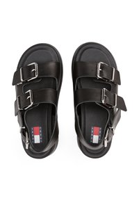Sandale din piele neagră, cu două curele reglabile cu catarame, talpă texturată și o talpă netedă. Logo în roșu, alb și albastru pe interior.
