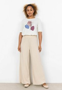Cream t-shirt with a graphic in blue and maroon, paired with beige wide-leg pants. Both garments feature a casual fit and soft texture.