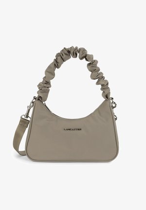 Borsa in tessuto beige con forma curvata, tracolla arricciata, hardware argentato e chiusura con zip. Presenta un logo in rilievo sul fronte.