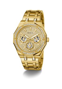 Montre Guess en ton or avec des embellissements en cristal, trois sous-dials pour les fonctions 24 heures, jour et date, et un bracelet en métal maillé.