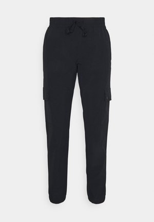 Pantalon cargo noir avec ceinture élastique, cordon de serrage et poches à rabat sur les deux cuisses, présenté sur un fond uni.