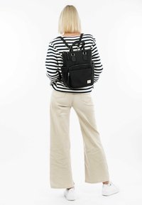 Black fabric backpack with dual top handles, adjustable straps, front zip pocket, and side pockets. Features a subtle textured design.