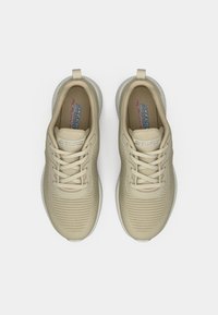 Beżowe sportowe trampki z teksturowaną cholewką, okrągłym noskiem i sznurowanym zapięciem. Posiadają miękkie podeszwy i logo na języku.