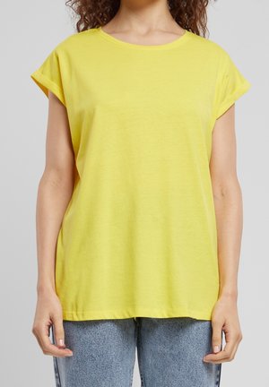 Geel T-shirt met korte mouwen en ronde hals, met een losse pasvorm, gemaakt van katoen, met opgerolde manchetten, gecombineerd met lichtblauwe spijkerbroek.