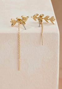 Zlati uhani z motivom lista, ki vključujejo verigo in paličico. Kovina z poliranim zaključkom; vključuje zatič za pritrditev.