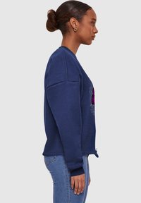 Felpa blu navy con maniche lunghe, polsini a coste e collo arrotondato; presenta una grafica sulla parte anteriore. La texture appare liscia.
