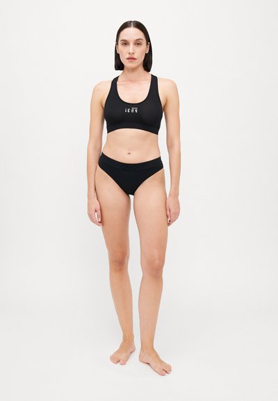 Black sports bra with logo and matching black bikini bottom, featuring a smooth texture and minimalistic design. Both items are unembellished.