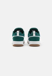 Turkoosin mokkanahkakengät valkoisilla yksityiskohdilla, kumipohja, pehmustettu kaulus ja logo kantapäässä. Siisti, moderni muotoilu.