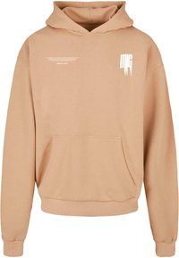 Kapuzensweatshirt in Hellbeige, aus weichem Stoff gefertigt. Verfügt über eine Fronttasche und minimalistischen weißen Text, der auf der Brust aufgedruckt ist.