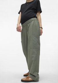 Groene, wijde broek van een textuurstof, met een elastische tailleband en grote zijzakken. Gecombineerd met een zwart, kortmouwtop.