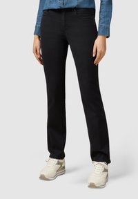 Svart jeans med rak benprofil gjorda av bomullsblandning, med fem fickor. I kombination med ljusfärgade, sportiga snörskor.