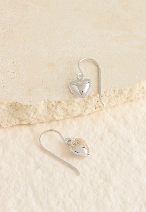 Sølv øreringe i hjerteform med en poleret overflade og delikate bølgede kanter, hængende fra en buet krog.