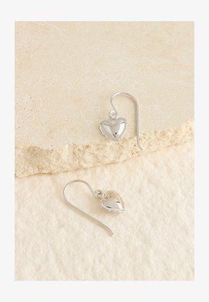 Sølv øreringe i hjerteform med en poleret overflade og delikate bølgede kanter, hængende fra en buet krog.