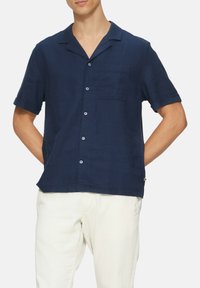 Kurzärmliges, navyblaues, knöpfbares Hemd aus strukturiertem Stoff, mit Kragen, einer einzigen Brusttasche und kontrastierenden Knöpfen.