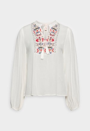 Biała bluzka z długim rękawem z kwiatowym haftem na piersi i sznureczkami do wiązania przy okrągłym dekolcie, z marszczonymi rękawami i elastycznymi mankietami.