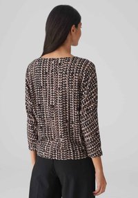 Langärmliges Oberteil in einem braun- und cremefarbenen Design mit einem gepunkteten Muster. Der Stoff ist weich, hat eine lässige Passform und einen Bootsausschnitt.