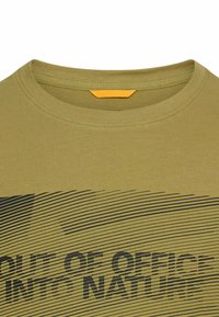 Olijfgroene katoenen t-shirt met ronde hals, voorzien van zwarte grafische tekst en lijnen over de voorkant. Gele label zichtbaar bij de halslijn.