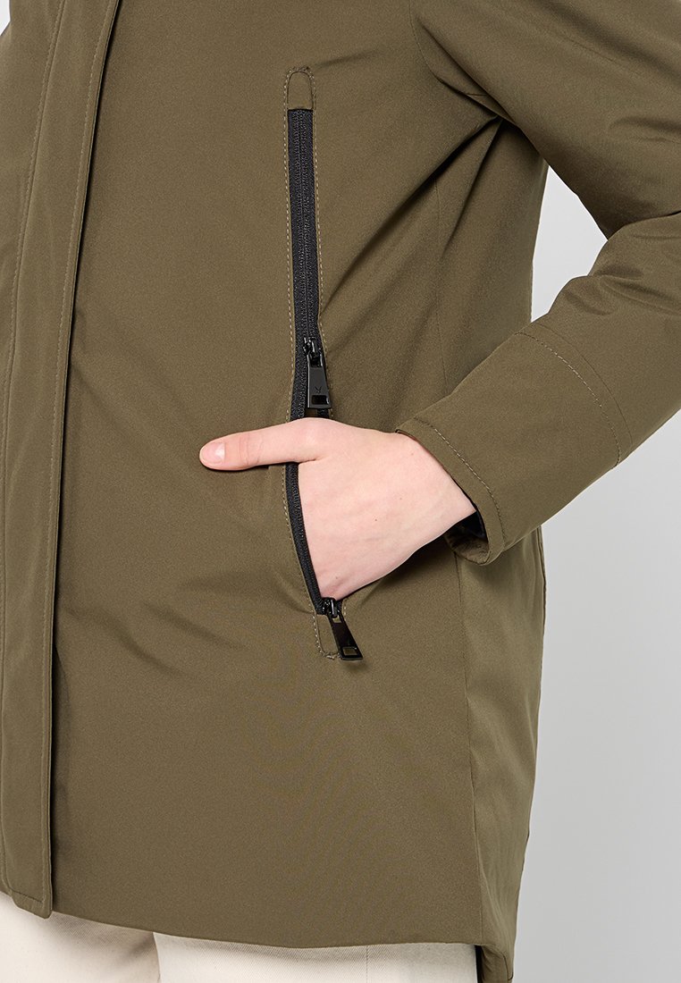 Veste olive verte avec fermeture éclair à l'avant et poche zippée sur le côté. Texture lisse avec une coupe ajustée et des détails de couture contrastés.