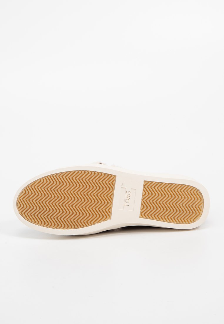 Baskets blanches avec une semelle en caoutchouc texturé présentant un motif en zigzag. Le logo de la marque est embossé dans la zone du talon. Design simple.