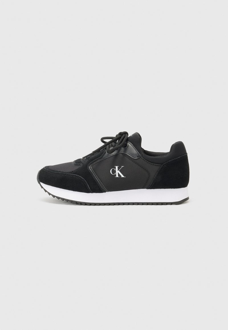 Black athletic shoes with a mix of leather and suede, featuring a white midsole, round laces, and a small printed logo on the side.