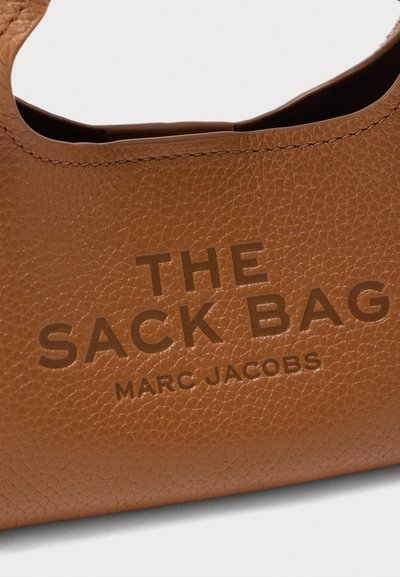 Καφέ δερμάτινη τσάντα με υφή από κόκκους, με ανάγλυφο κείμενο: "THE SACK BAG" και "MARC JACOBS." Στρογγυλές λαβές στην κορυφή.