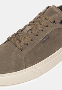 Sneaker in suede marrone con punta rotonda, finitura testurizzata, lacci coordinati, occhielli in argento e suola in gomma bianca con battistrada decorato.