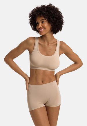 Beige sportbeha en bijpassende shorts van een gladde stof. De beha heeft een ronde halslijn en brede bandjes; de shorts hebben een aansluitende taille.