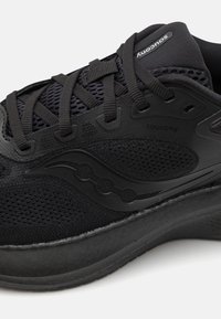 Scarpa sportiva nera con tomaia in rete e sintetico, caratterizzata da una suola testurizzata, un design curvo e un logo discreto sul lato e sulla linguetta.