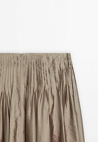 Jupe plissée taille haute en tissu taupe brillant avec une fermeture éclair au dos.