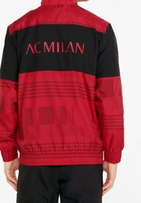 Rote und schwarze Windjacke mit "AC MILAN" Logo, ausgestattet mit strukturierten Mustern sowie elastischen Bündchen an der Taille und an den Ärmeln.